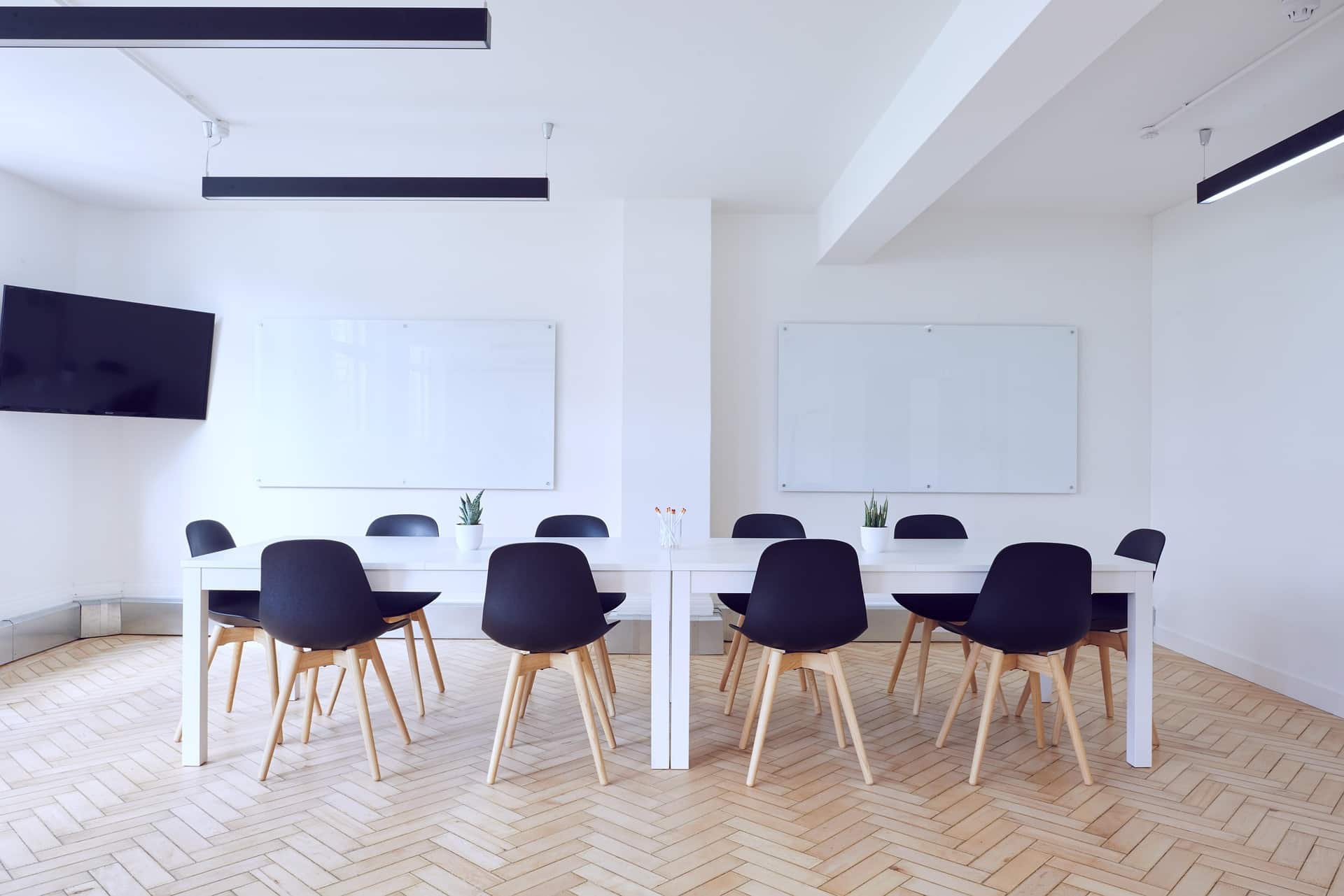 A spacious, modern conference room with a herringbone floor and whiteboards, illustrating the comprehensive setting for a Full Board Assessment by ebersmith coaching and consulting