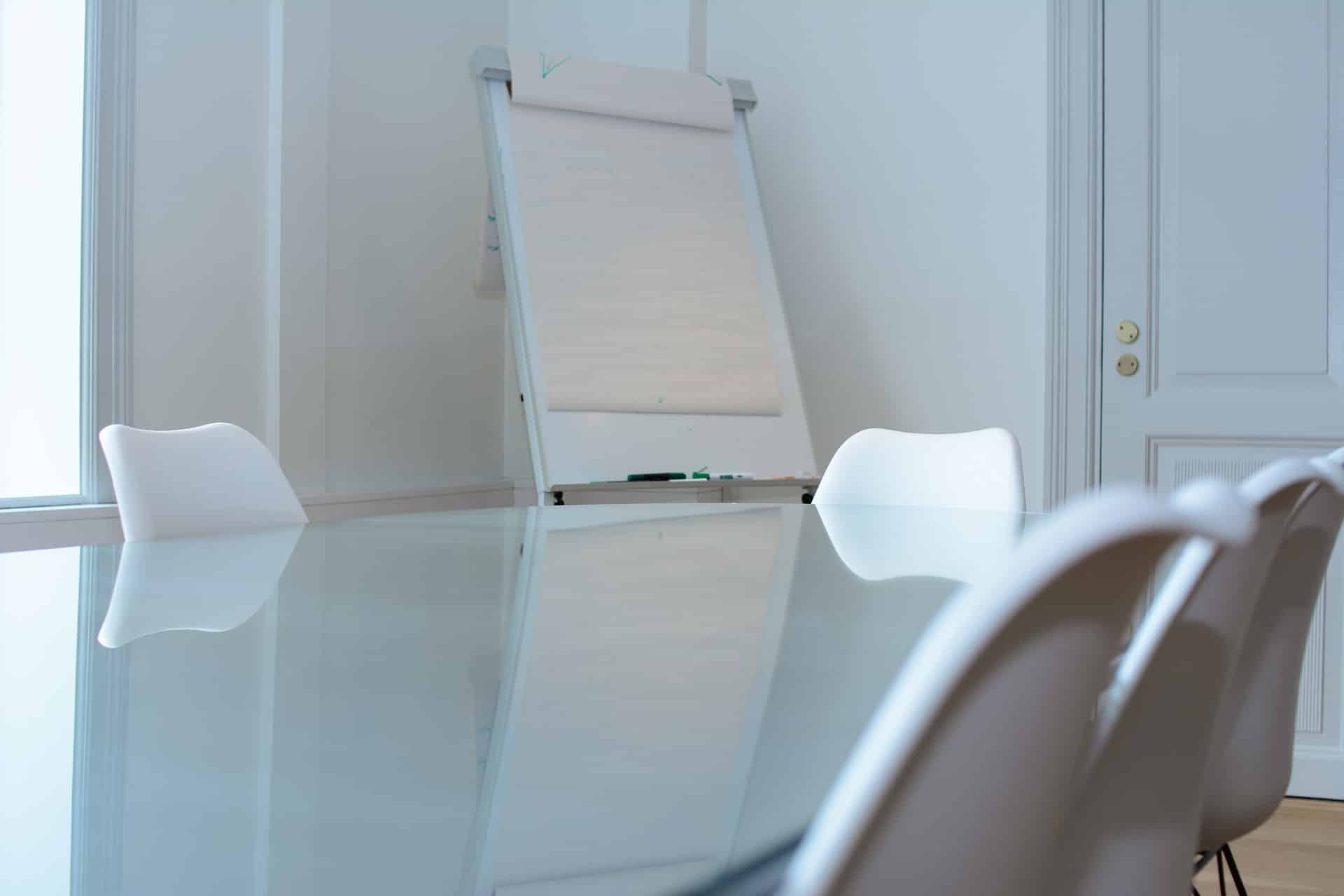 A modern, bright workspace with a white glossy table and easel, representing the focused environment of the Board Health Check Lite assessment for nonprofit Executive Directors and Board Chairs