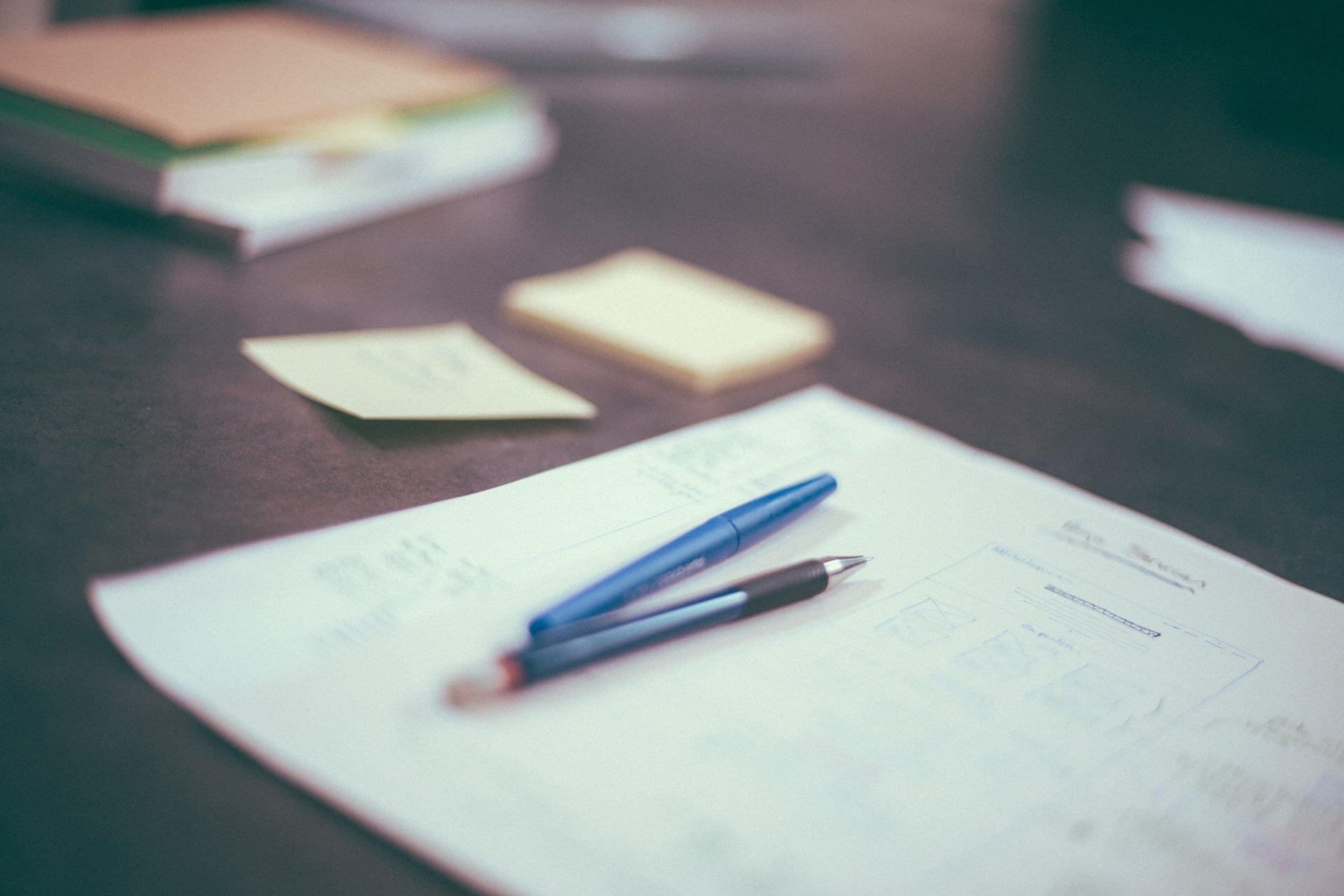 A close-up of executive governance documents and pens on a modern desk, representing the deliverables included in the Inherited Board™ New ED program by ebersmith coaching & consulting